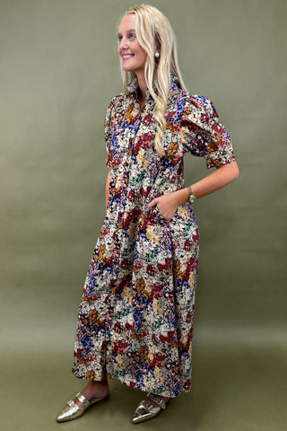 Woman wearing a colorful floral dress against a green background
