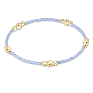 Bracelet with gold beads on a light purple cord against a white background