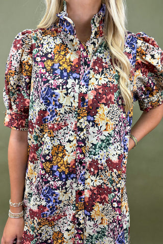 Woman wearing a colorful floral dress against a green background