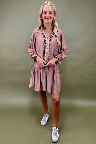 Woman wearing a pink dress with long sleeves and white sneakers on a green background