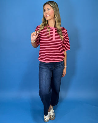 Pink and burgundy striped short sleeve knit top with a round neckline, button placket, relaxed fit, and contrast pink trim.