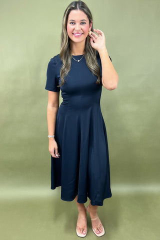 Woman wearing a navy blue dress against a green background