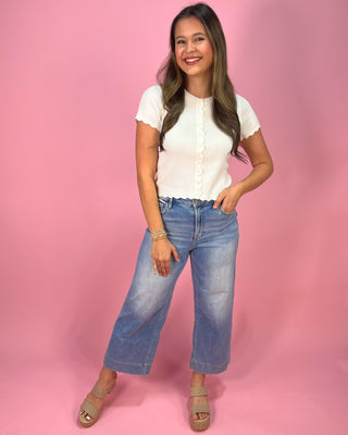 Woman wearing a white shirt and blue jeans against a pink background