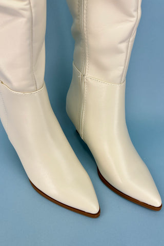 White knee-high boots with brown soles on a blue background