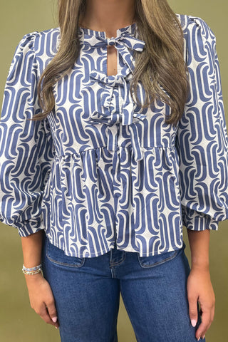 Woman wearing a blue and white patterned blouse with a green background