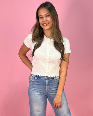 Woman wearing a white blouse and blue jeans against a pink background