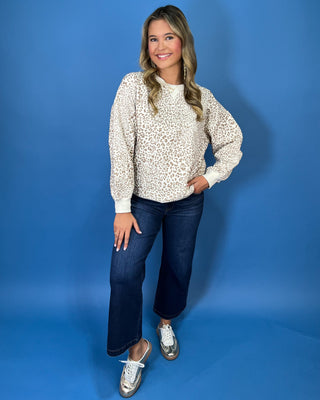 Ivory long sleeve sweatshirt with a taupe leopard print, classic crew neckline, relaxed fit, and ribbed trim.