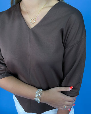 Person wearing a brown top with a blue background