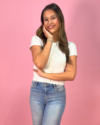 Woman wearing a white blouse and blue jeans against a pink background