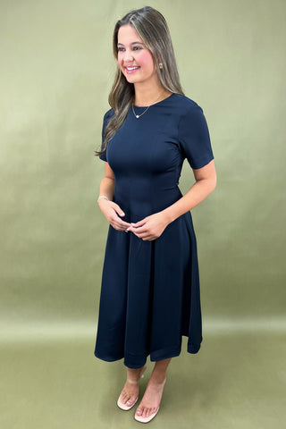 Woman wearing a navy blue dress against a green background
