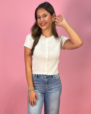 Woman wearing a white blouse and blue jeans against a pink background