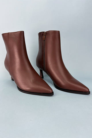 Pair of brown leather ankle boots on a light gray background