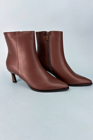Pair of brown leather ankle boots on a light gray background