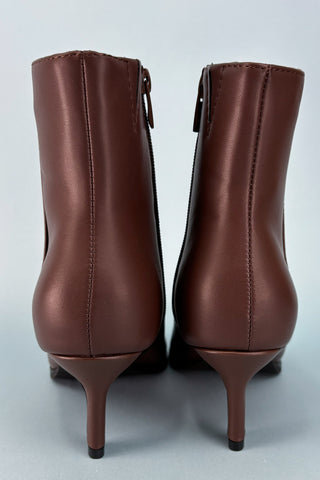 Pair of brown leather ankle boots on a light gray background