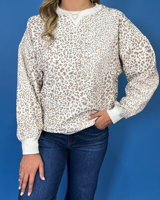 Ivory long sleeve sweatshirt with a taupe leopard print, classic crew neckline, relaxed fit, and ribbed trim.