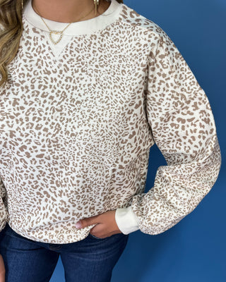 Ivory long sleeve sweatshirt with a taupe leopard print, classic crew neckline, relaxed fit, and ribbed trim.