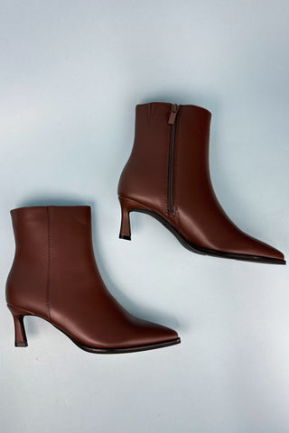 Pair of brown ankle boots on a light gray background