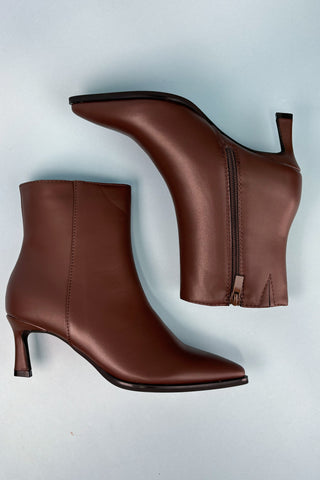 Brown leather ankle boots with a zipper on a light gray background
