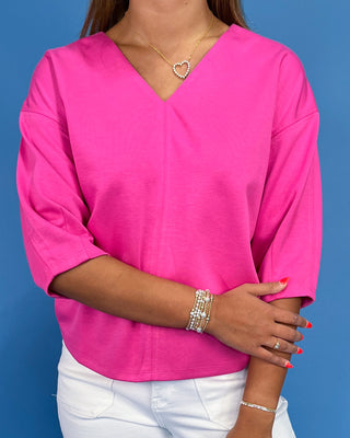 Person wearing a bright pink blouse with a blue background