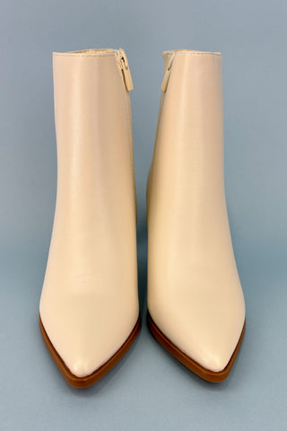 Pair of beige ankle boots with brown soles on a gray background