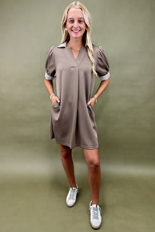 Woman wearing a brown dress with puff sleeves against a green background