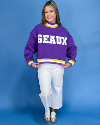Person wearing a purple sweater with 'GEAUX' text on a blue background