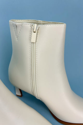 White ankle boot with a zipper on a blue background