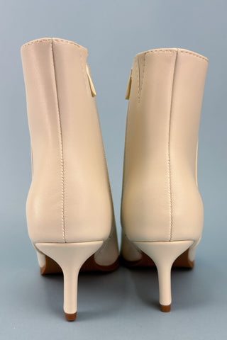 Pair of beige high-heeled boots on a gray background