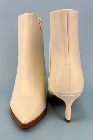 Pair of beige high-heeled ankle boots on a gray background