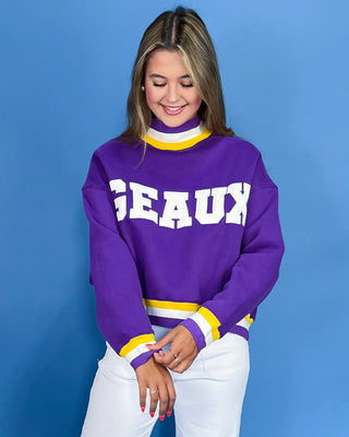 Woman wearing a purple sweater with 'GEaux' text on a blue background