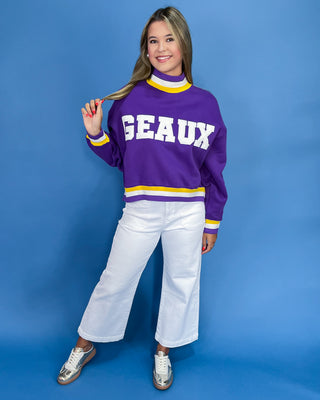 Person wearing a purple sweater with 'GEaux' text on a blue background