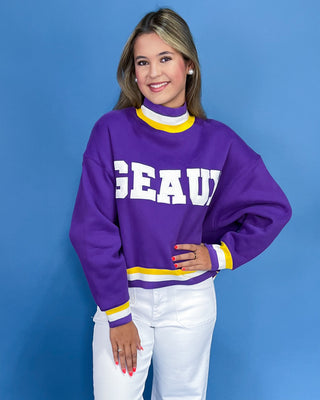 Woman wearing a purple sweater with 'GEAU' text against a blue background