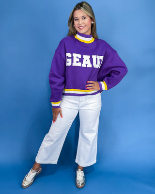 Person wearing a purple sweater with 'GEAU' text on a blue background