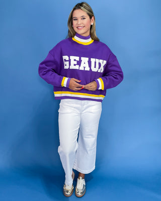 Person wearing a purple sweater with 'GEAUX' text on a blue background