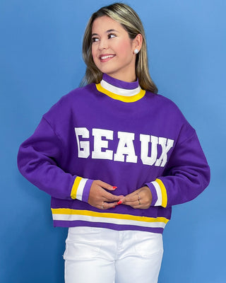 Person wearing a purple sweater with 'GEAUX' text against a blue background
