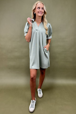 Woman wearing a light gray dress with white sneakers on a beige background