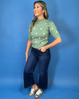 Sage green mock neck knit sweater top with white polka dots, puff shoulders, elbow-length sleeves, and ribbed trim.