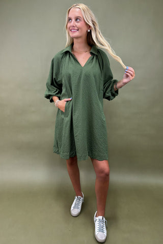 Woman wearing a green dress with white sneakers on a plain background