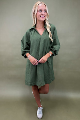 Woman wearing a green dress against a plain background