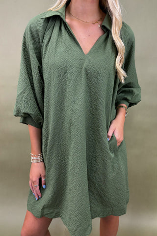 Green dress worn by a person on a plain background