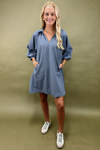 Woman wearing a blue dress with white sneakers on a beige background