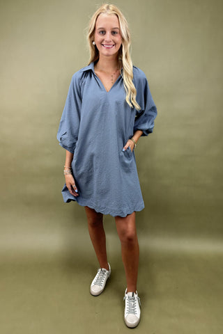 Woman wearing a blue dress with white sneakers on a green background