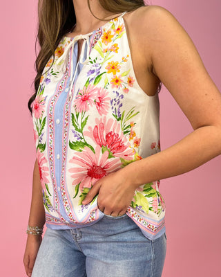 Woman wearing a floral sleeveless top with a pink background