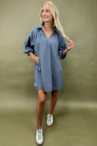 Woman wearing a blue dress with white sneakers on a green background