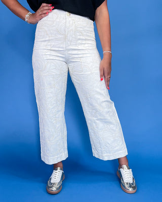 Person wearing white textured pants on a blue background