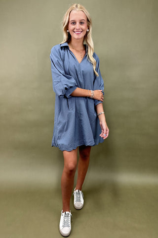 Woman wearing a blue dress with white sneakers on a green background