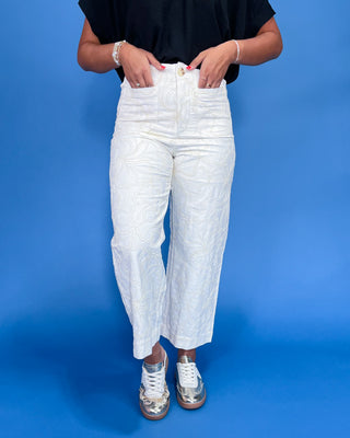 Person wearing white textured pants on a blue background
