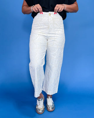 Person wearing white textured pants on a blue background