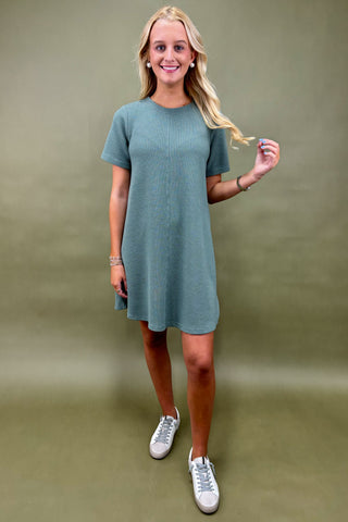 Woman wearing a teal dress against a plain background