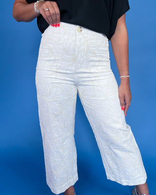 Person wearing white textured pants against a blue background